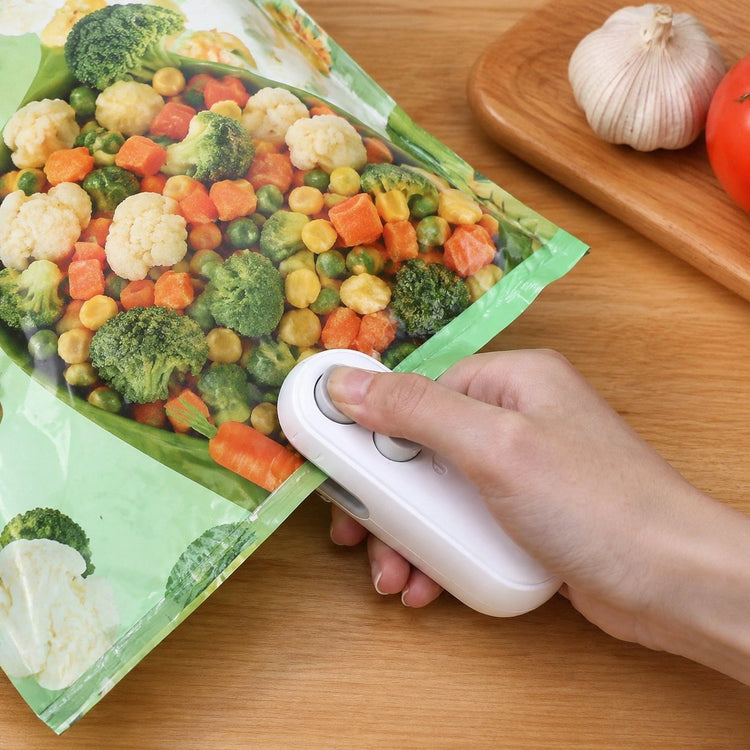 Hand using a white bag sealer on a vegetable bag