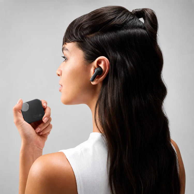 Person wearing a black Prelium CMT earbud and holding the charging case
